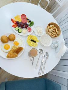 a white table with plates of breakfast food on it at Baiterek Premium in Astana