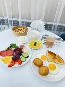 a table with plates of breakfast foods on it at Baiterek Premium in Astana