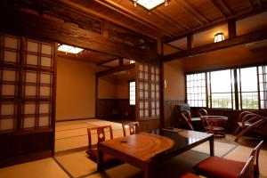 a room with a table and chairs and windows at Yunoyado Irifune in Aso