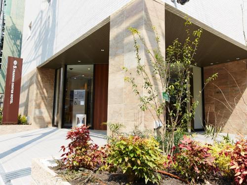 un bâtiment avec quelques plantes devant lui dans l'établissement S.Training Center Hotel Osaka, à Osaka