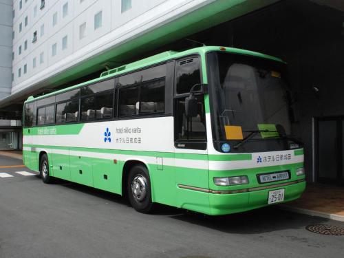 un autobus verde e bianco parcheggiato accanto a un edificio di Hotel Nikko Narita a Narita