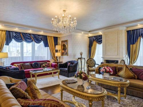 a living room with couches and a chandelier at Rixos President Hotel Astana in Astana