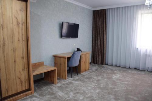 a room with a desk and a television on a wall at MirOtel Hotel in Astana