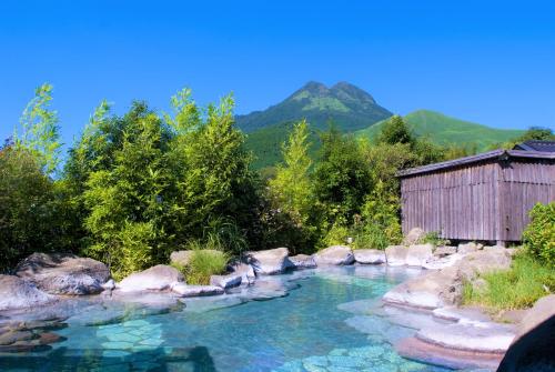 ein Wasserpool mit einem Gebäude und Bergen im Hintergrund in der Unterkunft Baien in Yufu