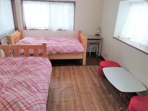 a bedroom with two beds and a table and a chair at Guest House Asora in Aso