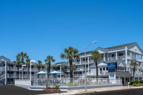 ein großes Apartmenthaus mit Palmen und einer Straße in der Unterkunft The Sandbar Hotel, Trademark Collection by Wyndham in Myrtle Beach