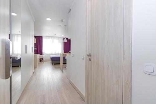 a room with a hallway with white walls and wooden floors at Отель у Ботанического Сада, в самом центре in Astana