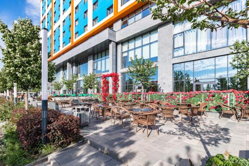 a patio with tables and chairs in front of a building at Отель у Ботанического Сада, в самом центре in Astana