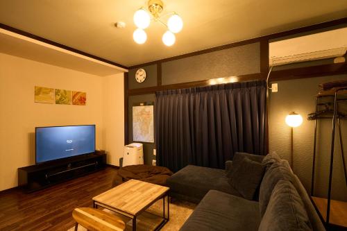 ein Wohnzimmer mit einem Sofa und einem Flachbild-TV in der Unterkunft 堀田フォレストハウス in Beppu