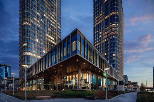 a large glass building with two tall buildings at The Ritz-Carlton, Astana in Astana