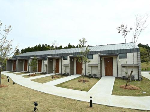 een groot wit gebouw met bomen ervoor bij Kosugi Resort in Aso