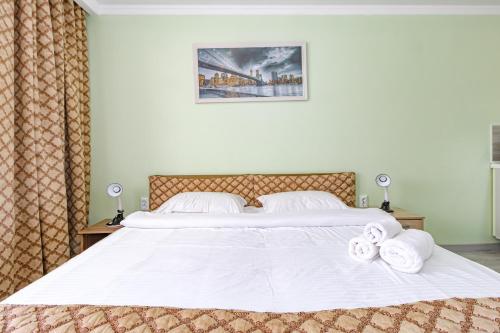 a bedroom with a white bed with towels on it at Expo Inn апартаменты напротив Ботанического сада in Astana