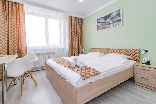 a bedroom with a bed and a desk and a window at Expo Inn апартаменты напротив Ботанического сада in Astana