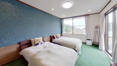 twee bedden in een kamer met een blauwe muur bij H,U,B Unzen - Vacation STAY 01672v in Unzen