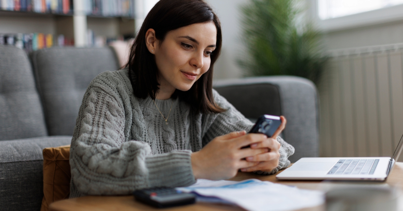 Self-payment for patients - A woman at home using her smartphone and laptop to check for her online medical bill.