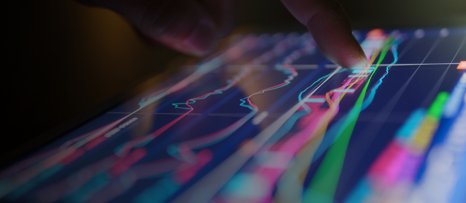 Closeup view of a finger on a digital screen displaying graphs