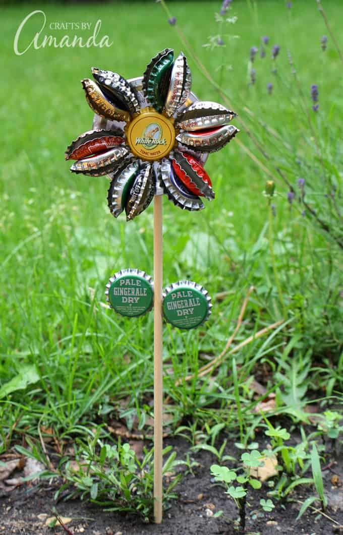 Turn old bottle caps into a rustic bottle cap flower to display in potted plants or right in your garden. Safe to leave outside too! #bottlecap #recycledcrafts #gardencrafts #adultcrafts #recycle #repurpose #earthday #summercrafts #springcrafts Rustic Bottle Cap Flower in garden