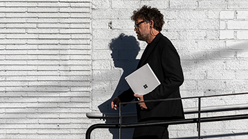 Un hombre caminando y sosteniendo un Surface Book