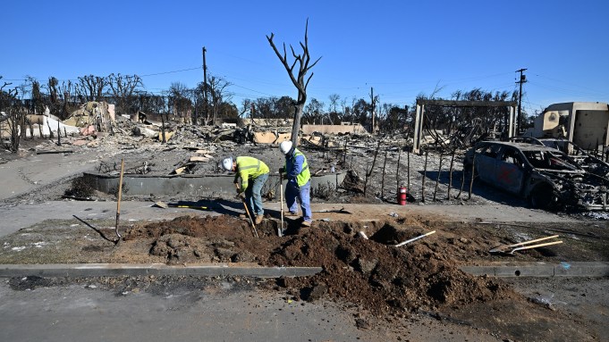 Workers dig to extinguish existing gas lines amid the debris of a house ravaged by the Palisades Fire