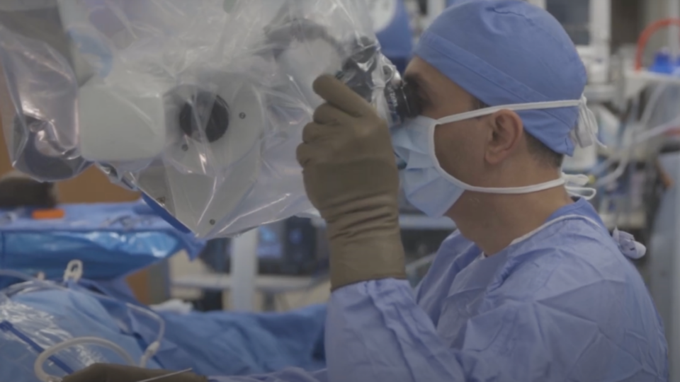 A surgeon using a medical device in an operating room.