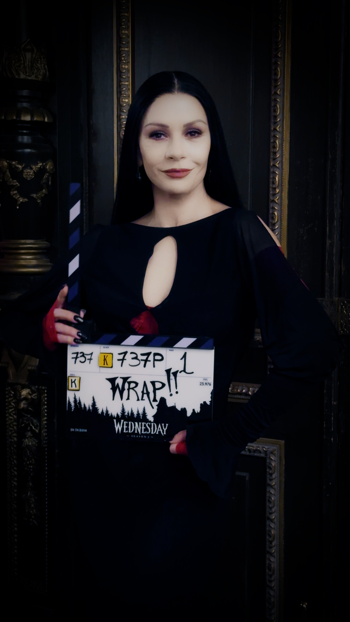 Catherine Zeta Jones as Morticia Addams holds a clap board for Season 2 of 'Wednesday'