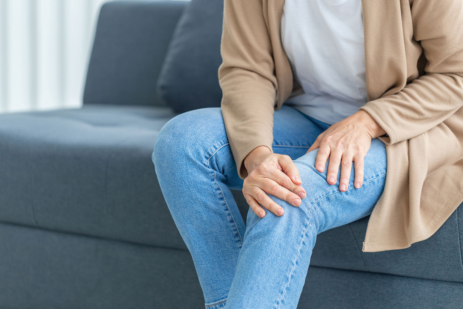 A woman sitting on a couch with her hands on her knees