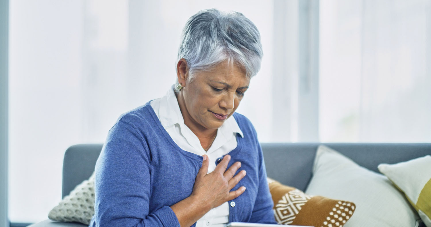 A woman sitting on a couch holding her chest