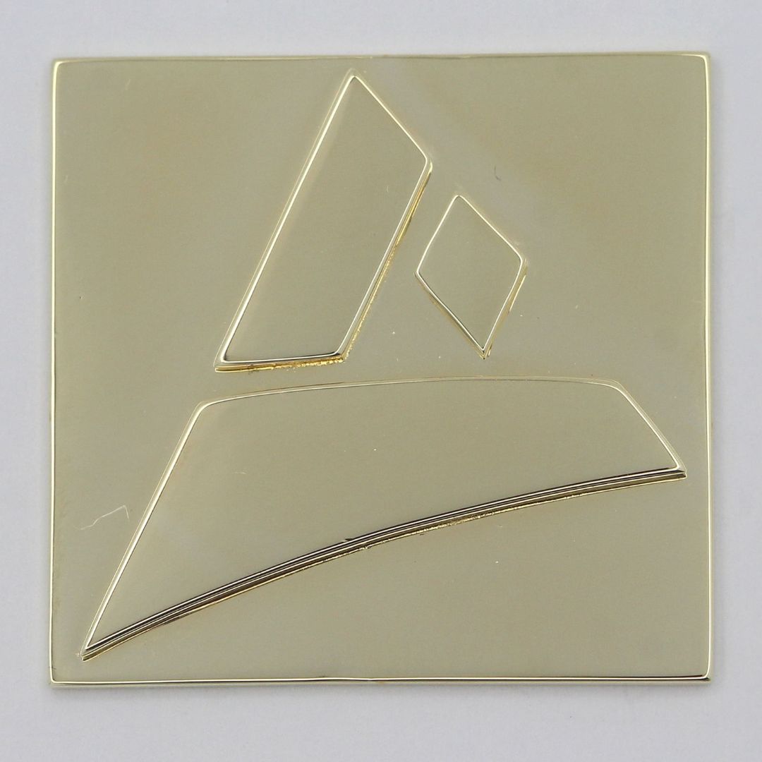 Casted sample of the Castimize logo in 14K yellow gold plated brass