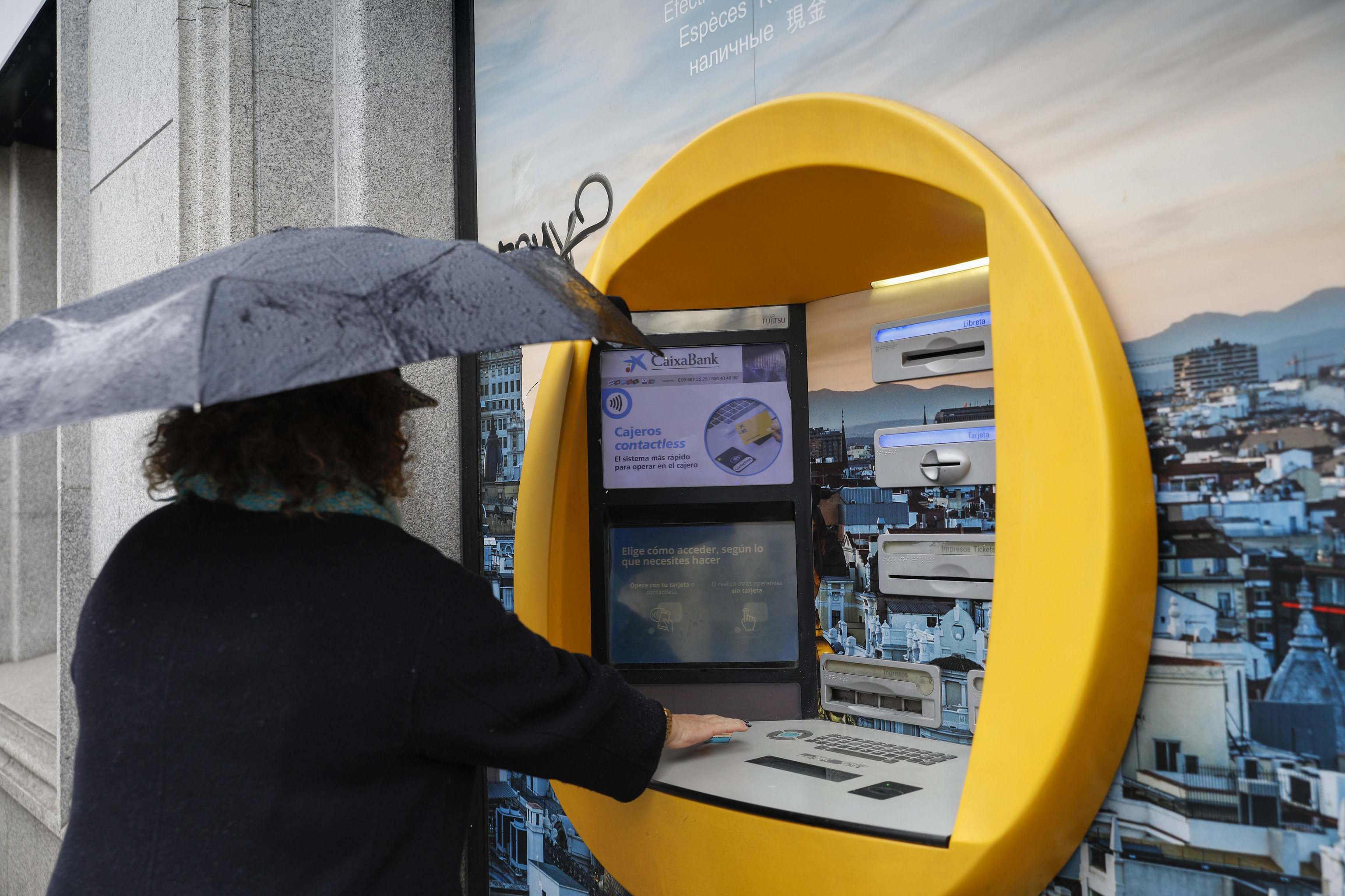 Una persona saca dinero del cajero autom�tico de una sucursal bancaria.