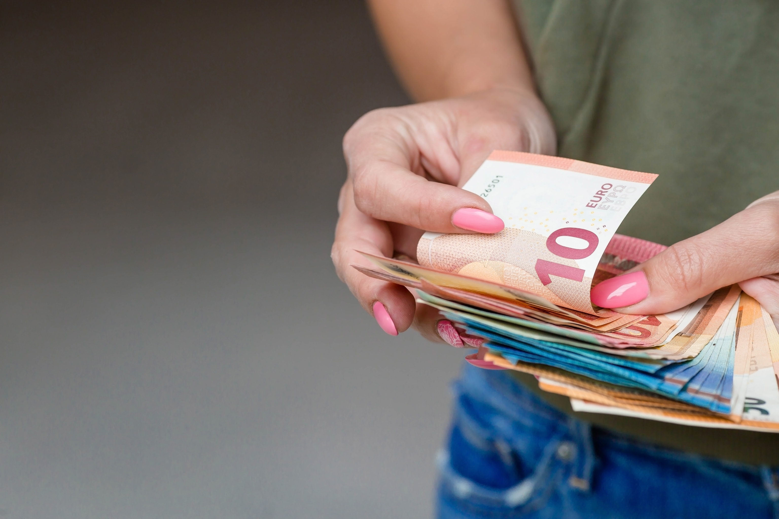 Una mujer con un fajo de billetes en la mano.