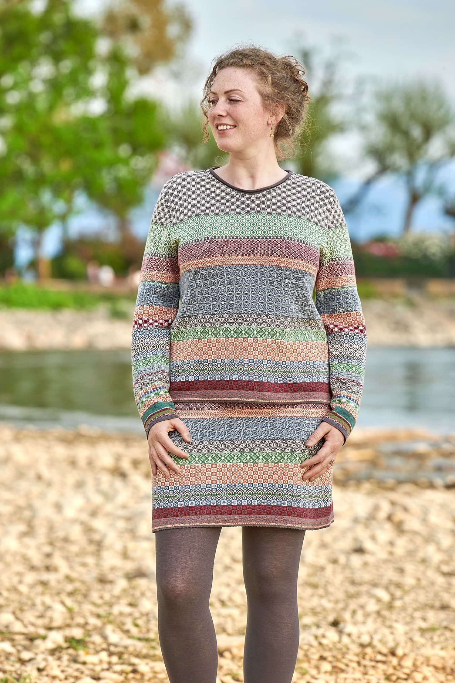 Baumwoll-Strickrock aus reiner Bio-Baumwolle Frau trägt einen gemusterten Rock und Strickpullover aus bio Baumwolle (kbA) und eine lila Strumpfhose
