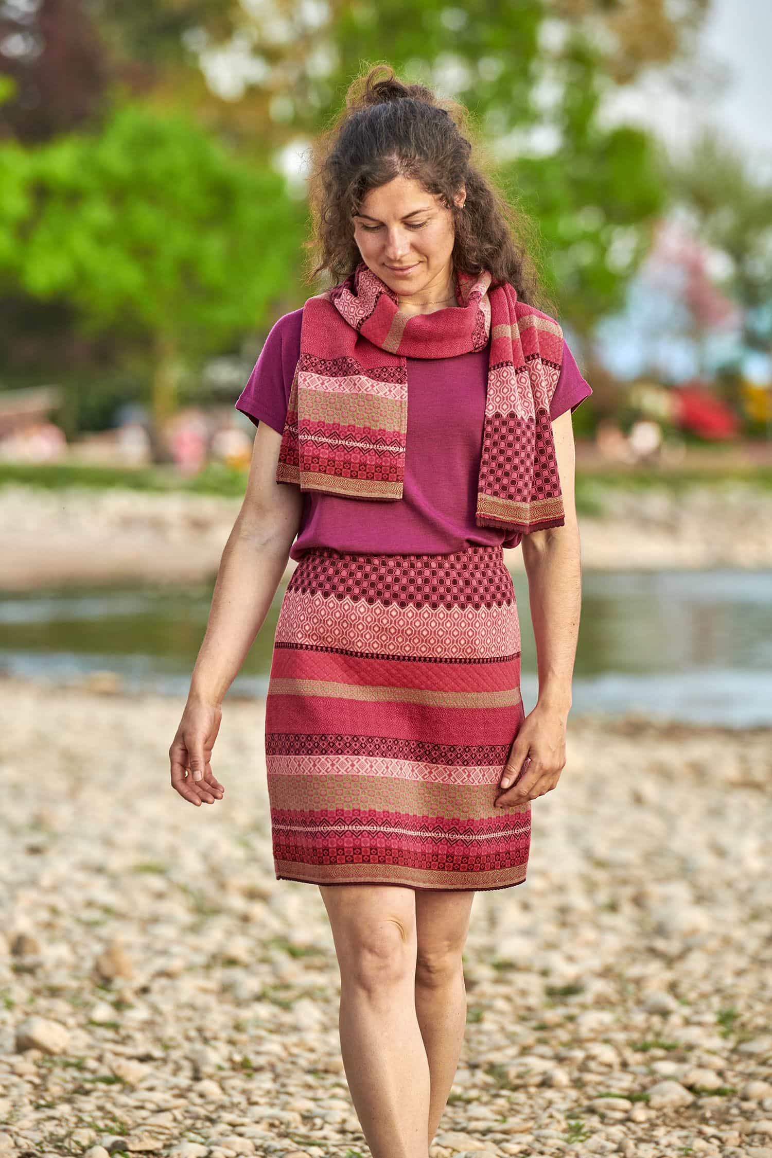 Baumwoll-Strickrock aus reiner Bio-Baumwolle Frau trägt einen gemusterten Strickrock in beere und pink aus bio Baumwolle (kbA), mit passendem Schal und lila Shirt