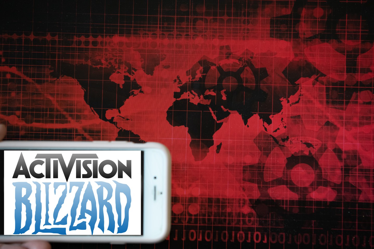 The logo of the gaming company Activision Blizzard is seen on a screen of a phone next to a red illustration of world