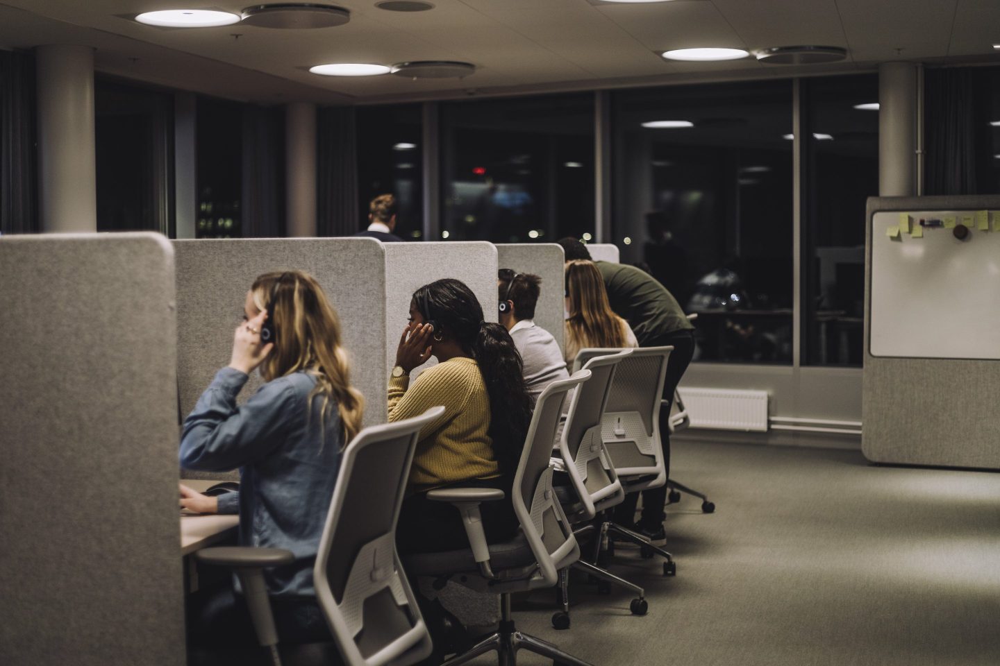 Multiracial team working side by side in illuminated call center.