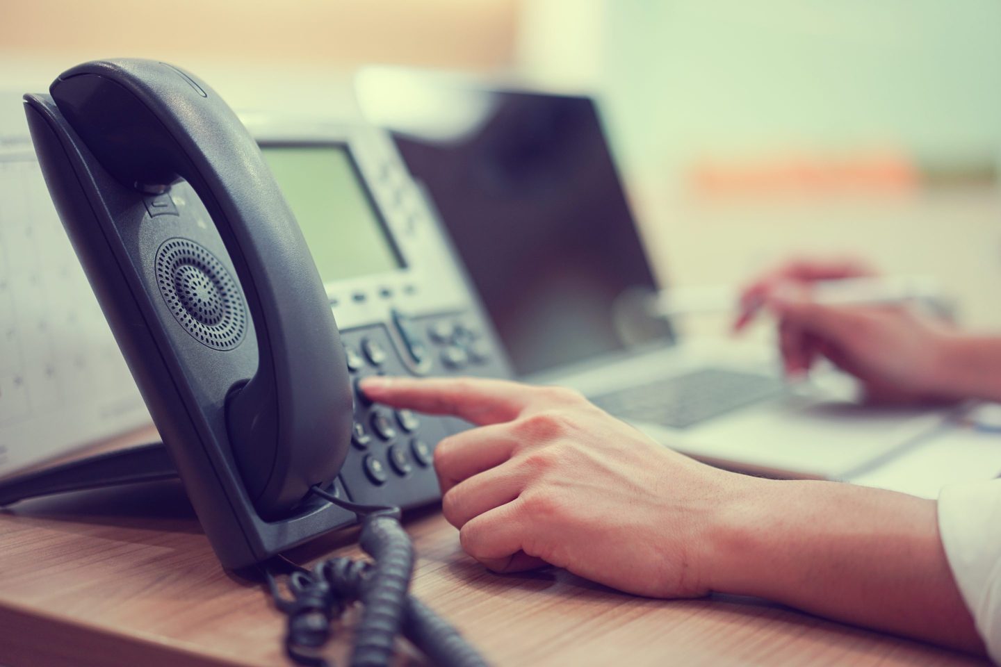 Close up of hand point to press button number on telephone office desk.