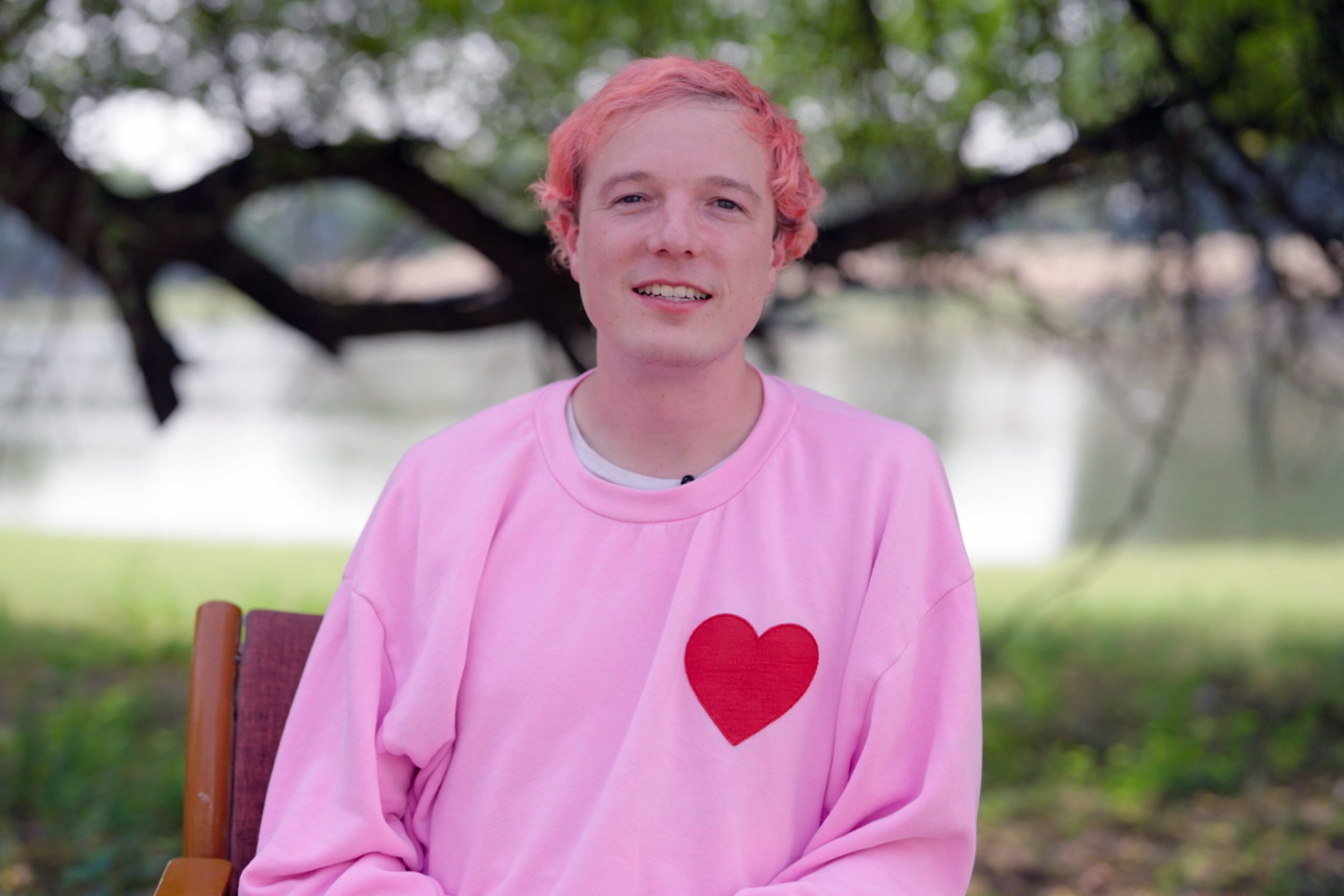 CEO and cofounder David Vorick sits in front of a tree wearing a pink sweatshirt with a red heart on it