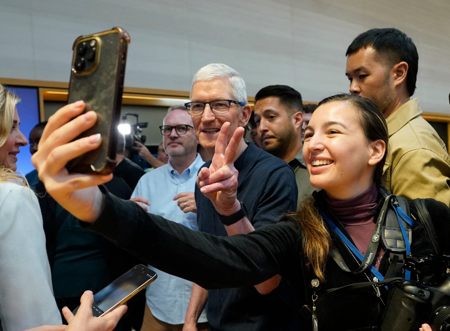 Apple CEO Tim Cook taking a photo with a fan at an Apple event.