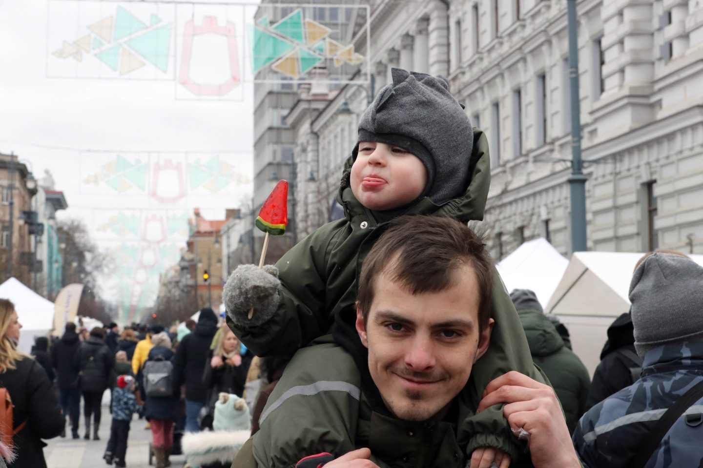 person smiling with a young kid on his shoulders