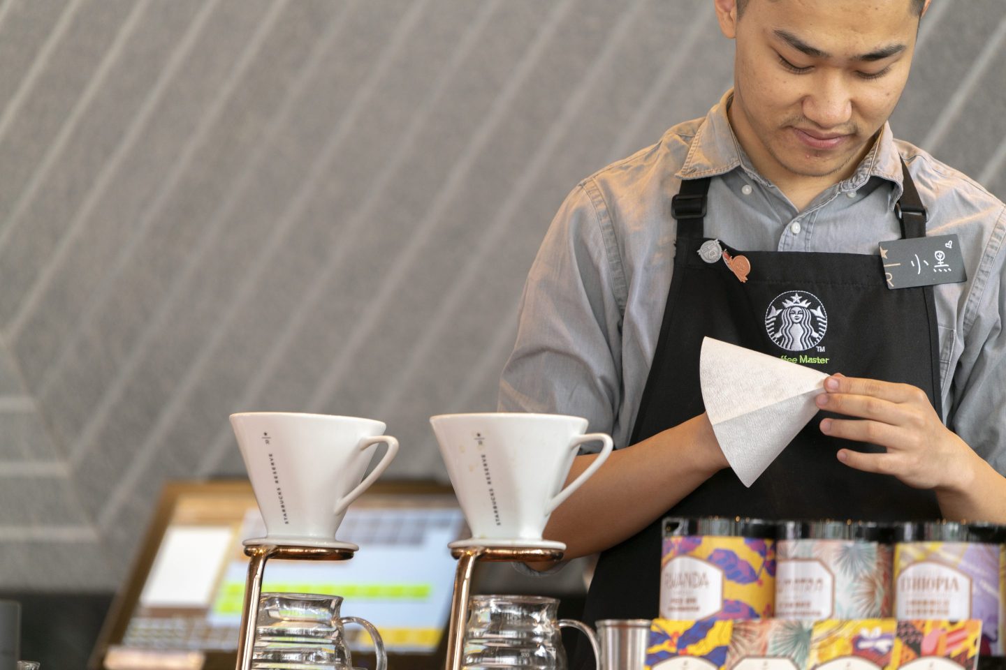 A Starbucks barista prepares a coffee filter behind the counter.