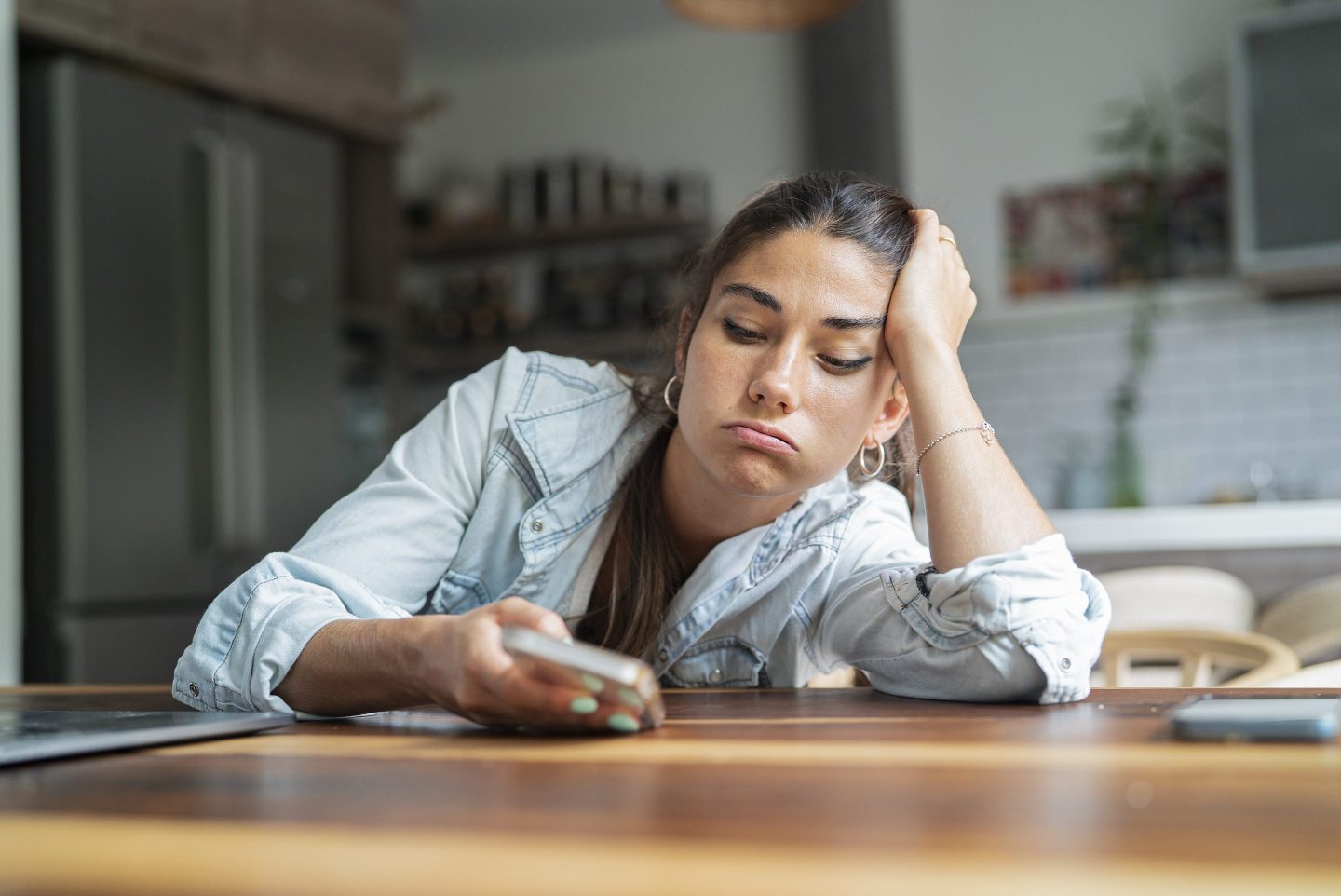 Portrait of bored young adult woman looking at smart phone