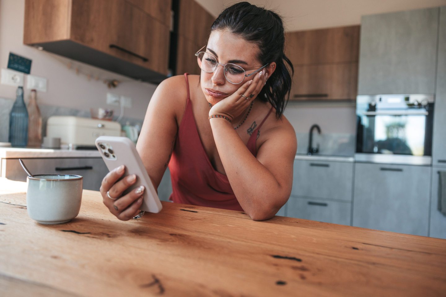 Woman checking her phone with her head leaned up against her hand.