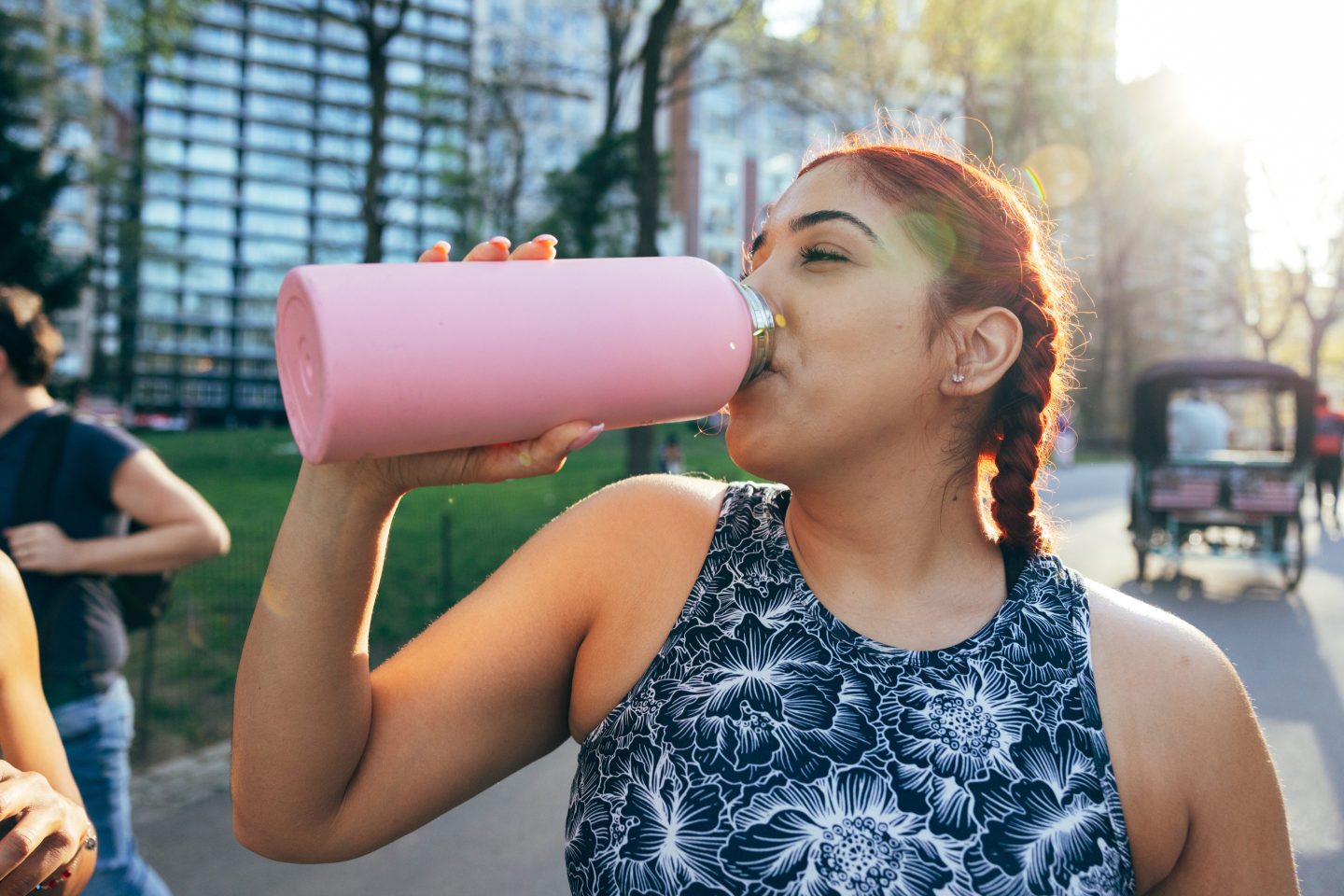 Photo of a young woman in a park drinking out of a water bottle