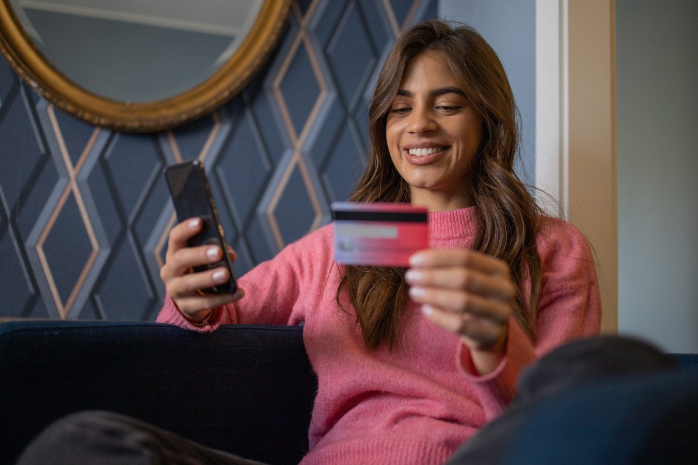 Woman holds a cell phone and a credit card.