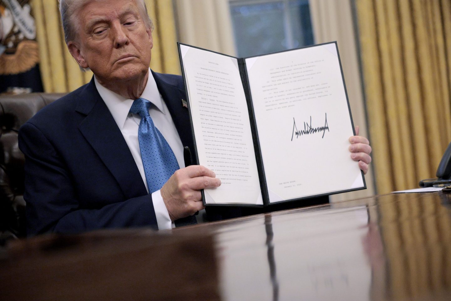 President Donald Trump holds up "Unleashing prosperity through deregulation,"  an executive order he signed on Jan. 31, 2025.