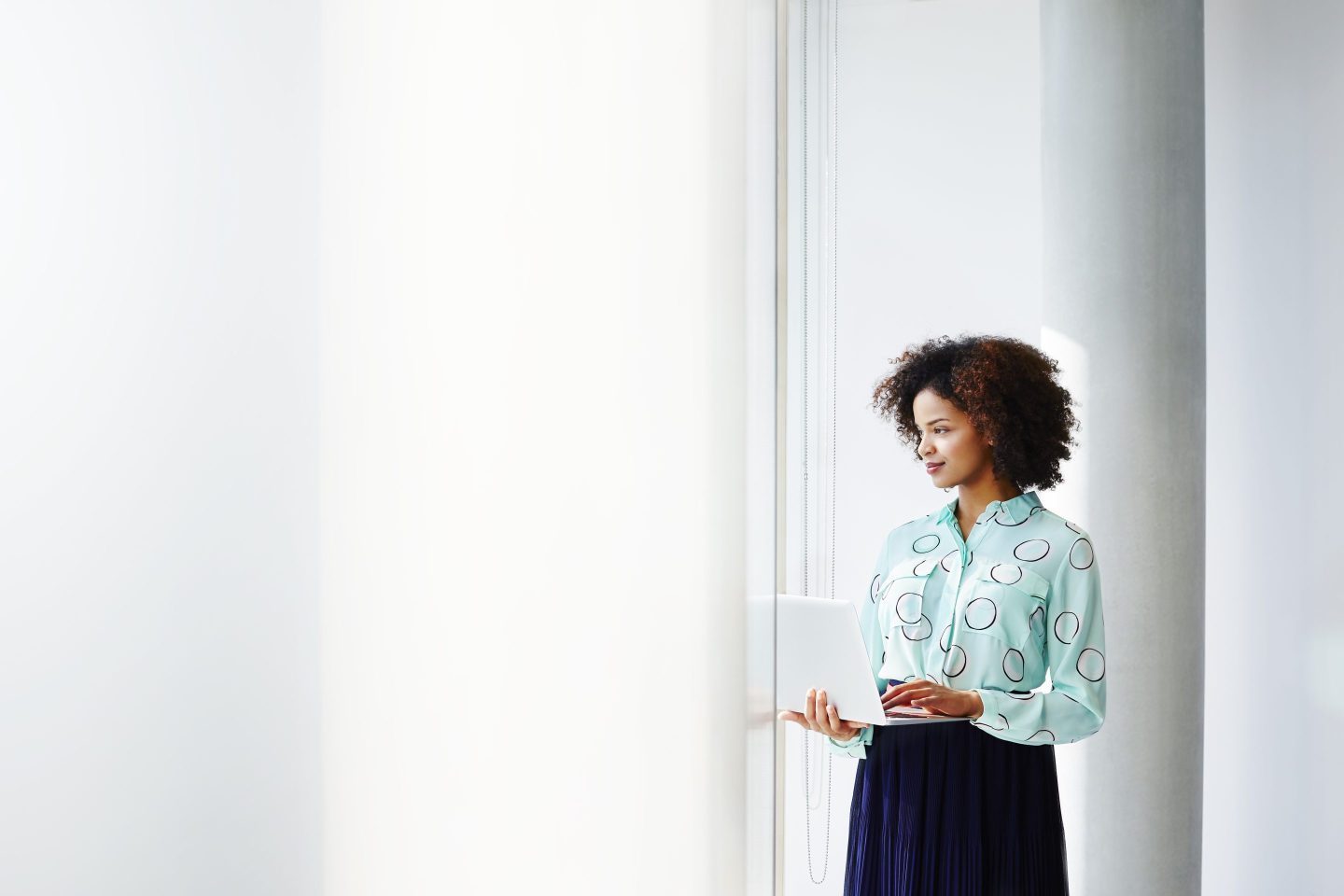 Businesswoman with laptop looking out of window