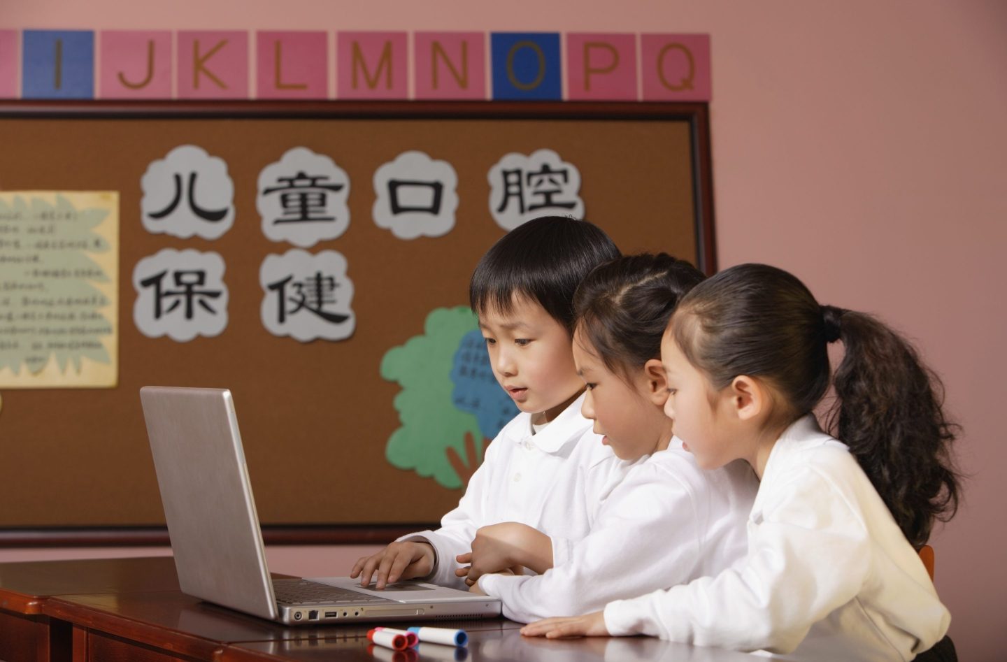 Young students play with laptop at school.