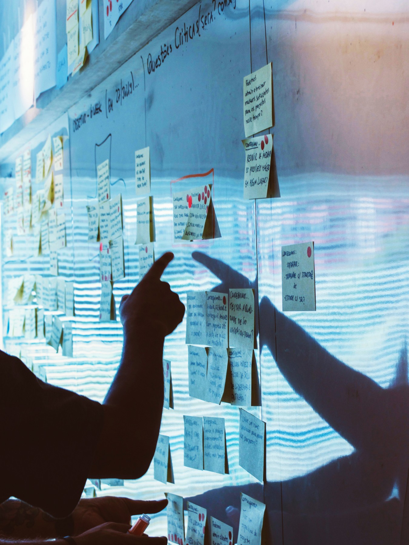 Two hands point towards a white board displaying data and graphs, suggesting collaboration or analysis.