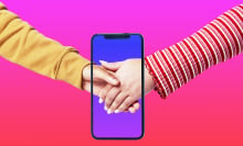 Gen Z couple holding hands through screen of smartphone