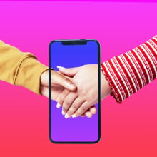 Gen Z couple holding hands through screen of smartphone