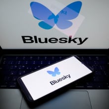 A glowing laptop screen and phone screen both display the Bluesky logo.